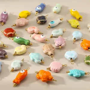 Detaillierte Nahaufnahme von bunten Keramik Fisch und Muschel Anhängern für DIY Schmuck.