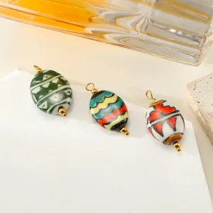 Close-up detail of hand-painted oval ceramic pendants with gold loops, perfect for DIY jewelry making.