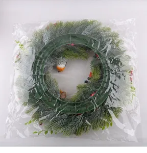 Closeup detail of artificial pine Christmas wreath with robin and berries in clear bag.