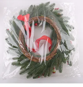 Vue détaillée de couronne de Noël avec aiguilles de pin, branches et nœud rouge déco.