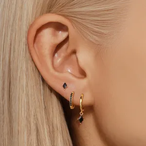 Detailed view of geometric gold earrings set featuring stylish black rhombus stone studs and hoops.