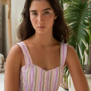 Close-up view of a minimalist gold clavicle chain with delicate heart charms worn by model.