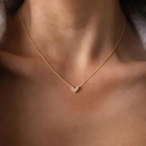 Close-up detail of dainty gold heart pendant necklace sparkling with cubic zirconia stones.