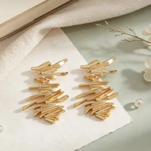 Vista dettagliata di orecchini dorati dal design astratto, gioielli eleganti donna.