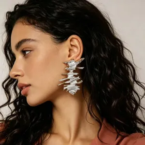 Orecchini pendenti argentati con linee astratte, dettaglio della texture metallica.