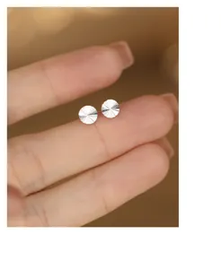Gedetailleerde close-up van kleine gefacetteerde ronde zilveren oorknopjes, fijne sieraden.