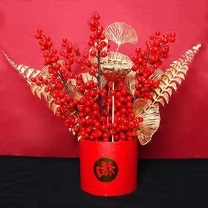 Détail d'arrangement de fleurs artificielles de baies rouges et feuilles dorées pot