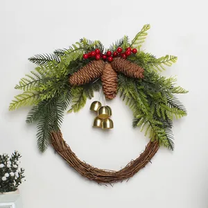 Christmas wreath detail featuring pine cones, red berries and golden bells for seasonal decor.