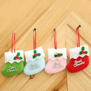Detailed view of mini Christmas stockings hanging, 4 assorted colors with plush trim and berries.