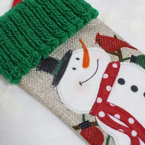 Handmade fabric Christmas stocking with cute snowman decor, burlap and green knit cuff.
