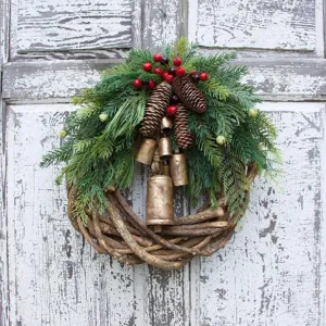 Rustic Christmas wreath with pine cones, red berries and brass bells for door decor.