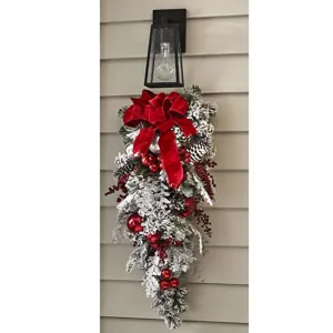Flocked Christmas teardrop swag with red velvet bow, pinecones and berries for door decor.