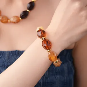 Close-up shot of geometric acrylic beaded bracelet in amber tones with gold spacer beads.