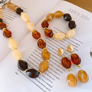 Detailed view of acrylic geometric beaded necklace, bracelet and earrings set in amber.