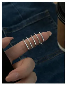 Detailopname van minimalistische S925 zilveren alfabetringen gedragen op vinger, stijlvol.