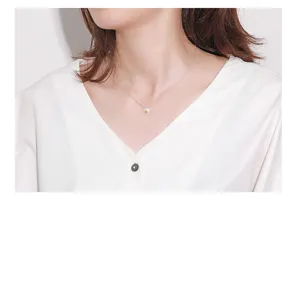 Vista dettagliata della collana con ciondolo a margherita in argento sterling indossata al collo.