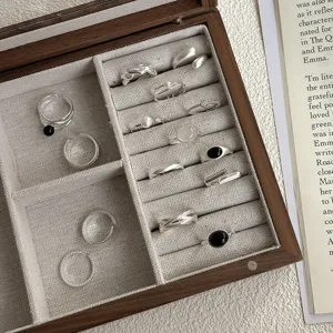 Gedetailleerd overzicht van minimalistische s925 zilveren ringen in een chique houten sieradendoos.