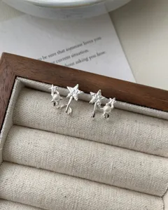 Close-up detail of silver star pearl earrings displayed in a wooden jewelry box.