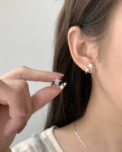 Close-up detail of S925 silver star and pearl earrings, minimalist chic style for women.