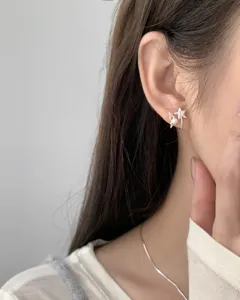Close-up of S925 sterling silver pearl and star ear studs showing delicate minimalist design.