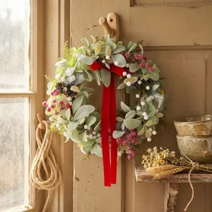 Christmas artificial flower wreath with red velvet bow and green leaves for holiday decor.