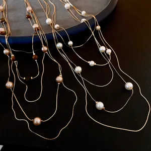 Multi-strand layered pearl and tiger eye necklace detail view featuring delicate gold chains.