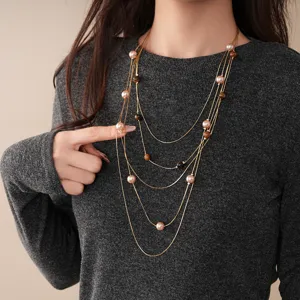 Close-up detail of the multi-strand pearl and tiger-eye beaded sweater chain pendant.