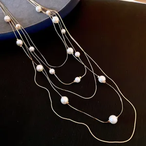 Elegant multi-strand pearl necklace, gold tone chain, stylish sweater accessory detail shot.