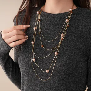 Close-up detail of multi-layer beaded pearl sweater necklace showing fine chains and stones.