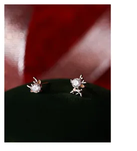 Primo piano dettagliato di orecchini asimmetrici a forma di corna di cervo con zircone.