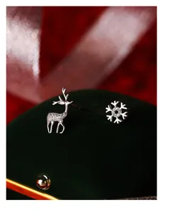 Primo piano dettagliato di orecchini a lobo con fiocco di neve e cervo in argento.