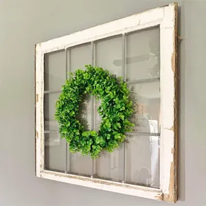 Detailed scene view of artificial eucalyptus wreath hanging on rustic white wooden window frame.