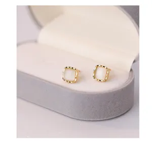 Gros plan de boucles d'oreilles carrées en œil de chat avec bordure dorée dans un écrin.