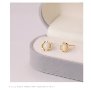 Gros plan détaillé de boucles d'oreilles clous en pierre d'œil de chat rondes.