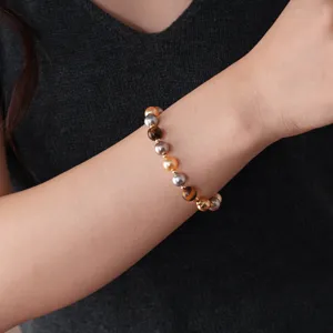 Detail shot of vintage style beaded bracelet with multi-color pearls and tiger eye stones.