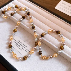 Detailed close-up of retro Maillard style tiger eye and pearl beaded jewelry in beige box.