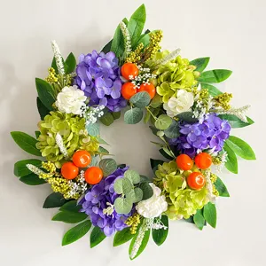 Corona de flores de hortensia artificial con pequeñas naranjas para la puerta de casa.