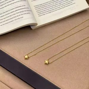 Vista detallada de dos collares con colgante de estrella 3D minimalistas bañados en oro