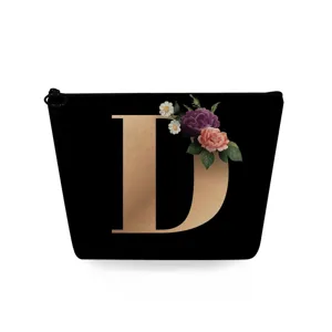 Gedetailleerd overzicht van de zwarte cosmetische tas met gouden letter D en bloemenprint.