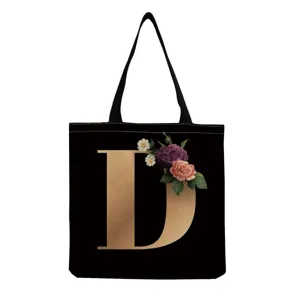 Black canvas tote bag featuring a elegant gold letter D and vintage floral print design.