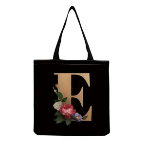 Black canvas tote bag with gold letter E and vintage floral print, casual shopping bag.