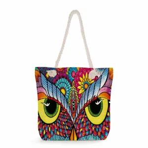 Detalle de estampado de búho colorido en bolso de playa de lona con asas de cuerda.