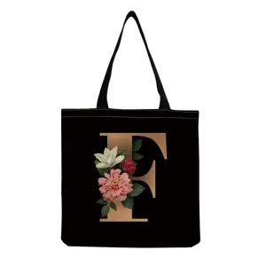 Black canvas tote bag featuring a vintage floral letter F print detail for daily shopping use.