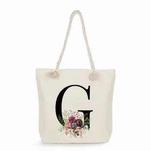 Segeltuch Tragetasche Detail mit elegantem schwarzen Blumen Buchstabe G Druck und Seilgriffen.