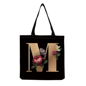Black canvas tote bag with gold letter M and floral print, casual daily shopping handbag.