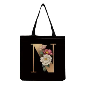 Canvas tote bag with elegant black and gold letter N floral print for daily shopping use.