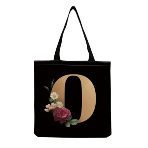 Black canvas tote bag featuring a golden letter O and vintage floral print design details.