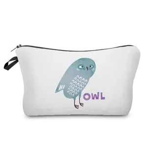 Detailed view of white cosmetic pouch with blue owl print and zipper closure.