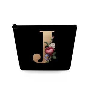 Detail van zwarte make up tas met gouden letter J en bloemenprint voor handige opslag.