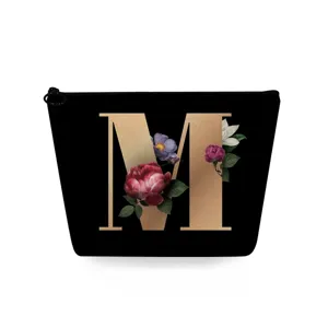 Detail van make-up tas met gouden letter M en elegante vintage bloemenprint ontwerp.